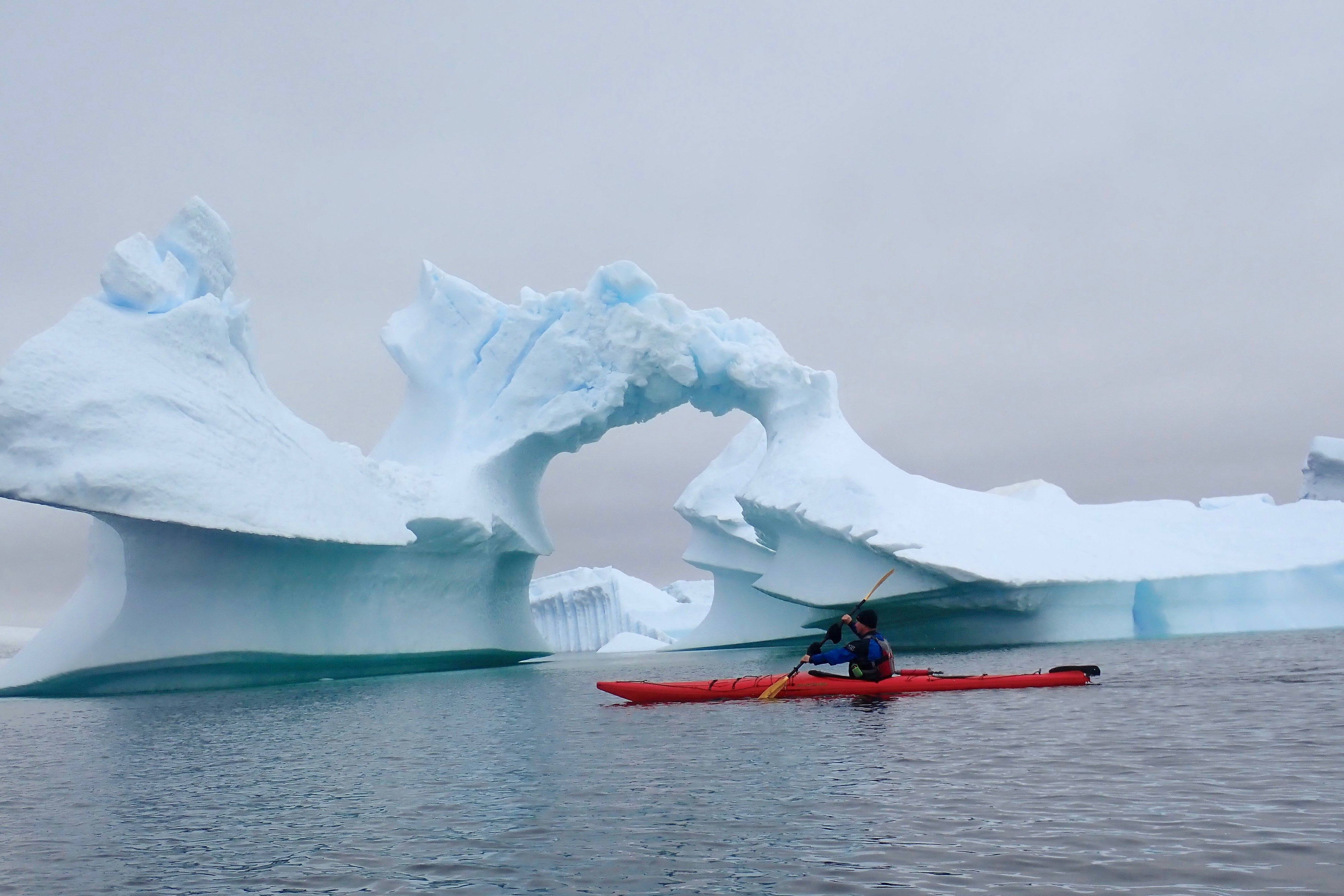 Mark paddling past iceberg arch
